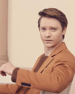 Calum Worthy, seated in a chair, facing the camera
