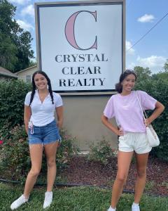 Crystal's daughters in front of new Crystal Clear Realty sign