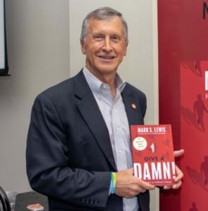 Portrait of Mark S. Lewis Holding his Give A Damn book