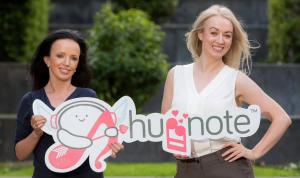 Huggnote founders Jacqui and Perry Meskell holding a Huggnote logo sign
