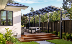 This backyard contains epi wood decking with a black metal L arbor and synthetic turf.