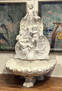 Late 19th century Italian Carrara marble wall fountain, richly carved with three putti on a vine cartouche and a large shell-shaped basin with scrolled feet, 75 inches high, 51 inches wide.