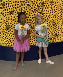 Olivia Ogleton (7) and Hadley Ryan (6) smile with sunflowers after enjoying the Immersive Van Gogh experience