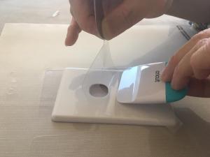 Applying the cut-out light switch protector to the wall panel of the light switch