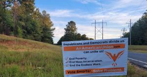 An orange and black campaign sign for the American Union pledges to end poverty, end mass incarceration, and end the endless wars.