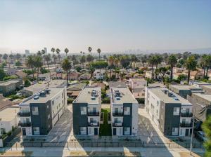 10 unit Multi-Family property on La Brea Ave., Los Angeles, CA. Gray and white building, surrounded by palm trees. Sunny California weather.