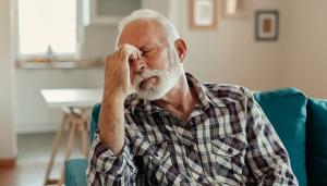 A man with a white beard sits on a coach, closing his eyes and rubbing the bridge of his nose.  People with depression can qualify for Social Security Disability benefits. Disability lawyers help with this process.