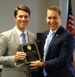 Attorney Garrick Harding standing with a plaque donated by Palm Beach County State's Attorney Dave Aronberg.