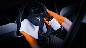 Dr. Beasley's Vegan Leather Cleanser being sprayed onto a cloth inside a Tesla