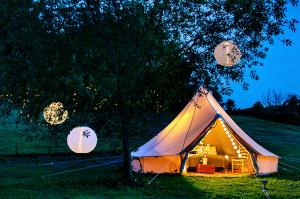 Photo of a large bell tent with a bed and tables.  A glamorous experience.