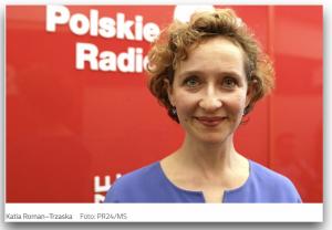 with curly light brown hair, dressed in a purple blouse, Katia Roman-Trzaska stands in front of the bright read logo of Polskie Radio  looking directly into the camera