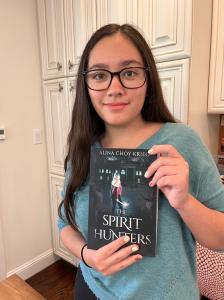 14-year-old author Alina Choy Krieg poses with her debut novel The Spirit Hunters