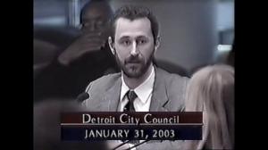 This image shows the founder of the Interstate Traveler Company, Justin Eric Sutton, answering questions from members of Detroit City Council on January 31st 2003