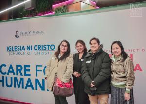 A group of women smiling in front of the Care For Humanity poster