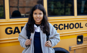 A student poses in front of a bus