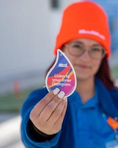 Car wash employee holds up brightly colored air freshener