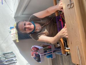A woman weaves on a loom specially equipped so people of all ages with any disaabilities can make art.