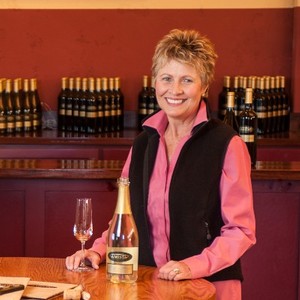 Woman smiles and holds a glass of wine.