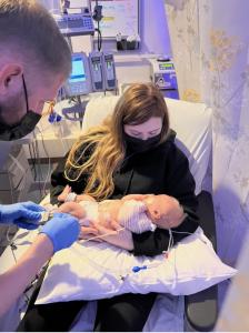 Mother Savanna Brown cradles Zeke wile NICU nurse attends to baby.