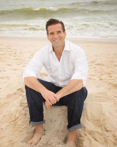 Rockin Wellness Founder Seth Luker sitting on a sand dune at the beach