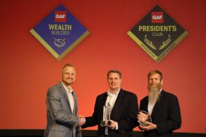 GAF's Tyler Milner Presents 2022 President's Club Award Trophy to Elite Roof and Solar Owners Mick Koster and Ross Erickson at GAF's Annual Conference