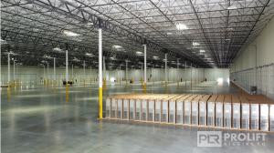 Image of empty warehouse interior.  High ceilings, clean floor without crates or any other stored materials