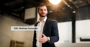 CEO Matthew Schneider standing in a black suit with a white collared shirt, in action pitching e-States' crowdfund campaign