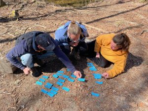 A Trails Carolina student and her parents sit on the ground outside and work on an emotional process and communication activity using flash cards.