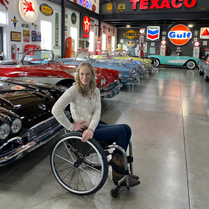 Woman in a wheelchair smiling in an old car museum