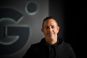 Brett Kaufman, CEO and Founder of Kaufman Development, is pictured in front of a logo for Gravity, the world's largest conscious community.
