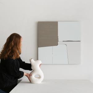 Woman placing vessel on table in front of "Hidden Energy 1" artwork hanging on wall