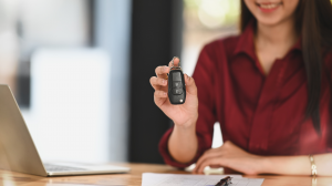 A woman holds up a key fob for a car, representing Veritas Global Protection’s dedication to low car protection prices