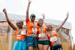 Four senior athletes stand on the podium with their gold medals after winning the women's 65+ 4x100 relay race by a wide margin at the 2023 National Senior Games.