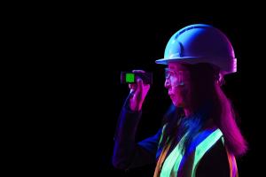 Image of a STEM worker in a hard hat pointing a measuring tool