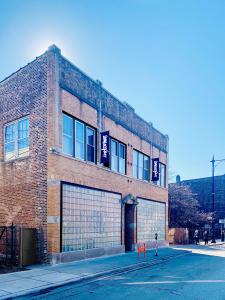 A photo of a two story building with two large glass block windows on the front and two banners (black with white writing) that say Someoddpilot. There is sidewalk and street in the foreground.