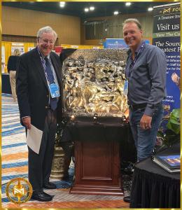 Mark Russo, CEO of Treasure Investments Corporation, standing next to Steve Forbes of Forbes Media in front of Michelangelo's Pure Silver Battle of the Centaurs as posthumous original on display at FreedomFest 2023 in Memphis in the Treasure Investments C