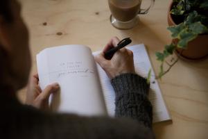 As a person pours thoughts into a journal, the ritual of reflection and faith anchors us amidst life's relentless pace.