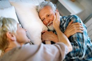 happy senior couple embracing in bed