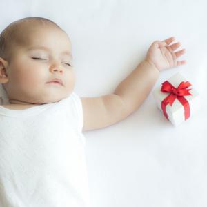 Baby sleeping on back with a small gift on the side