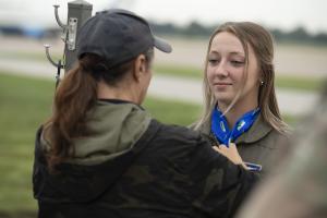 Captain Mama dressing up a teen girl in her flight suit