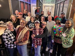 Group of people standing in front of axe throwing lanes wearing festive clothing and colors.