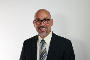 Image of a business man wearing glasses and smiling at the camera. Caption reads: Michael Rodriguez, ex-CFO, business advisor and Baylor University professor, explains strategic approaches to help HR leaders navigate the challenges of budget season and se