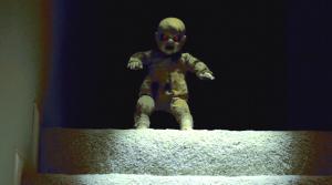 A scary doll on the dark at the top of a staircase