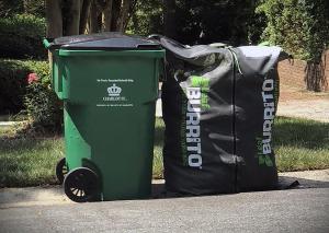 A Leaf Burrito lawn waste bag is full of compostable waste and sitting on the curb next to a City of Charlotte, NC trash cart.