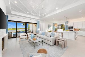 Stylish living room in GL Homes Valencia Parc at Riverland, Port St. Lucie, with modern furnishings and a view of palm trees through large windows.