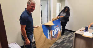 An image of CRO Greg Price and Branch Manager Genny Mukes looking at the new sign for the office being opened.