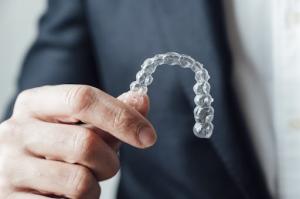 Man holding a clear aligner.