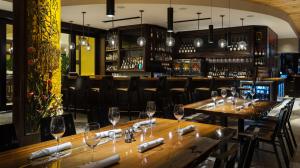 Upscale restaurant bar with elegant wood accents, pendant lights, and set tables ready for guests.
