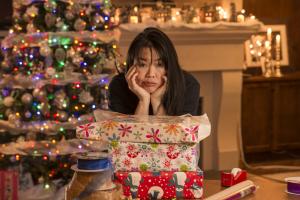 A woman is overwhelmed wrapping holiday gifts. Holiday stress can derail wellbeing.