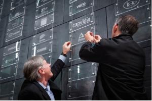 Two men attaching plaque to wall.